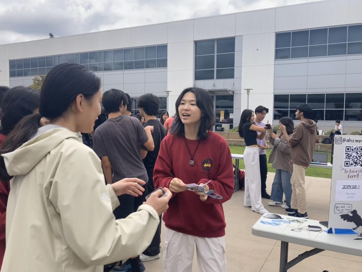 Improv Club president senior Catherine Pei hands out flyers to prospective members.