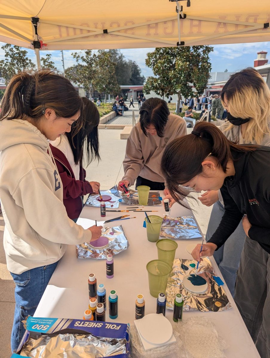 Students gathered around the table during lunch to express their creativity through painting