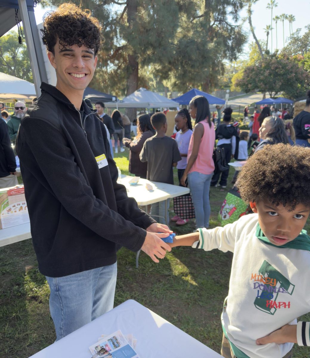 Jake Garcia putting a temporary tattoo on a child at the Youth4ward booth during the Christmas festival